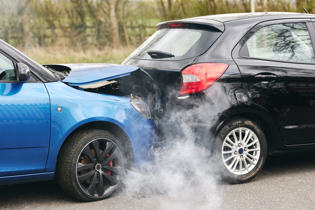 Two cars with rear-end collision damage and smoke on an Arizona roadside after a traffic accident